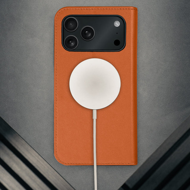 MagSafe charger attached to the Stand function of the Orange Leather Case for iPhone 17 Pro Max