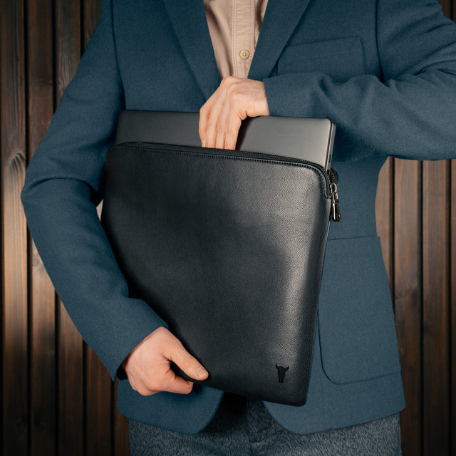 Man taking a laptop out of the Black Leather Laptop Sleeve with Zip Closure